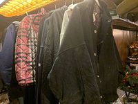 Photo showing eight jackets hanging on a rack, including a red plaid jacket, quilted black jackets, and others.