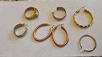 Overall view of men's gold band ring and earrings including two pairs and two single earrings