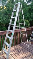Side view of 8 ft aluminum step ladder showing six steps on climbing side and paint marks.