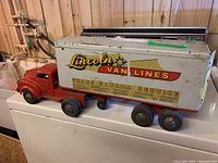 Full left-side view of red truck cab and white trailer on a surface