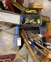 Overview of lot showing three metal military-style boxes containing chains, hooks, pulleys, and a foldable shovel with a wooden handle.