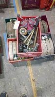 Several folded canvas fire hoses stacked surrounding crates with fire hose connectors, nozzles, and a red hydrant valve inside crates.