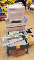 Photo showing three expandable rakes on top of a green gardening stool and two stacked storage totes (clear and beige). A beige bucket is visible.