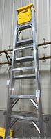 Full view of the 7-foot metal ladder with yellow plastic paint shelf mounted at the top.