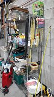 Full view of the metal wire shelving unit with multiple household items stored on the shelves. Unit against concrete block wall in garage setting.