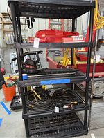 Front view of the shelving unit showing multiple shelves with various items placed, dusty and in a garage environment.