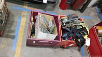 Crates with various straps, tie-downs, and tools on warehouse floor.