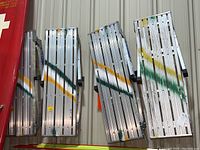Four aluminum folding platforms hung on wall, visible spray paint