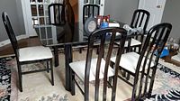 Set of six black lacquer finish dining chairs around a matching table, showing overall condition and style.