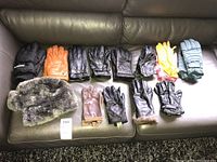 Full view of the lot showing all gloves and faux fur hat on brown leather couch.