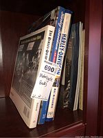 Side view of six motorcycle books standing upright on a shelf, includes titles referencing Harley-Davidson.