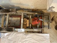 Overhead view of the metal motorcycle jack frame with red hydraulic bottle jack and wooden blocks inside the frame.