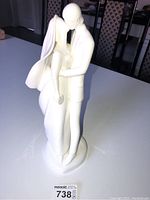 Front and side views of the Royal Doulton Wedding Day figurine featuring a bride and groom in an embrace, showing details of the dress, veil, and suit, with an off-white matte finish.