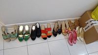 Photo showing all eight pairs of shoes lined against a wall on tile floor