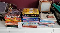 Stacked DVDs including Simpsons seasons 1-6, Titanic, Reno 911, Friends and more, with a yellow Simpsons-themed carrying case on top