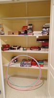 Photo of shelf with assorted boxed games, poker chips, 2 hula hoops leaning against shelf, various magazines and boxes