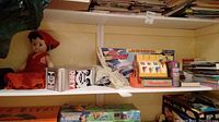 Vintage Fisher Price cash register, vintage doll, children's books, Obey can, and other toys on shelf