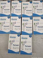 Photo showing 10 boxes of HCG Wreadycare infrared thermometers arranged on a surface.