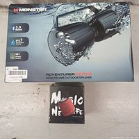 Top view of the two speaker boxes showing Monster Adventurer Force branding, Bluetooth 5.0, IPX7 waterproof rating, and 18+ hours battery life on the larger box and a smaller box with 'Music Note Portable Speaker' text.