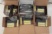 Seven black LED tactical flashlights in cardboard boxes, each with battery chargers and yellow rechargeable batteries in plastic cases. Batteries appear to be lithium-ion type 18650.