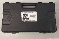 Closed black plastic molded carrying case with label indicating electric jack for car, 12V lighter powered, max lifting range 42cm.