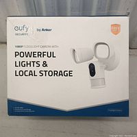 Front of factory packaging showing Eufy 1080p Floodlight Camera with powerful lights and local storage branding.
