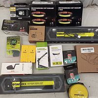 Photo showing 14 pieces including USB rechargeable soft headlamps in 2-pack boxes, Block Diamond spot headlamp, LED signal lights, pedometers, vehicle accessories, and other items arranged on a table.