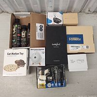 Overview of lot showing various boxed pet products including cat toy, bark control devices, and grooming products.