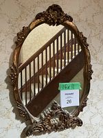 Front view of the vintage gilt resin framed oval mirror hanging on the wall under stairs.