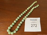 Full view of 40 graduated jade beads laid in two strands showing overall length and bead size progression.