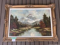 Full view of framed landscape painting showing ornate gold-toned carved wood frame and overall condition