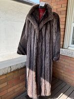 Front view of full-length raccoon fur coat on mannequin outdoors