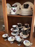 Cabinet display showing teapot, sugar bowl, creamer, stacked plates and cups
