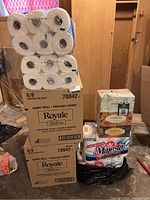 Stack of Royale Ultra giant roll boxes and Majesta tissue packages shown in a basement setting.