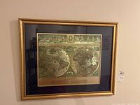 Framed Blaeu world map hanging on wall, showing entire frame and glass covering the map.