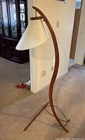 Full view of lamp showing curved teak frame and tripod base