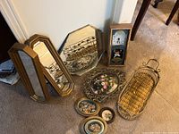 Wide shot showing all items: two composite frame octagonal mirrors, round bevel mirror, Elgin clock with dried flowers, multiple framed dried flower pieces, and wicker basket.