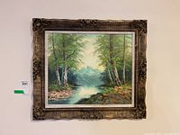 Frontal photo of the framed painting showing detailed landscape and ornate frame