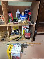 Wooden cubby with assorted painting supplies including brushes, rollers, cans, trowel, and caulking tool.