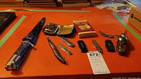 Full view of all items on an orange surface including pocket warmer with case, four pocket cutters, and a vintage spork utensil.