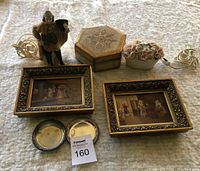 Assorted vintage decorative items including miniature framed paintings, figurine, small metal trays, flower container, wooden box, and night lamps arranged on carpet.