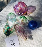 Photo showing all five glass friendship balls and ornaments arranged together on fabric background with auction tag visible.