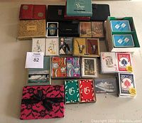 Large assortment of vintage playing cards and card game decks with multiple designs and companies, laid out showing boxes and packaging