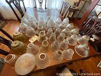 Table layout of 31 antique glass lamp shades of various styles and sizes
