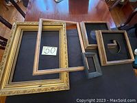 Top view of five antique picture frames arranged on wooden table, varying styles and sizes shown.