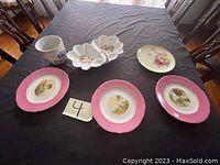 Full view of four plates, divided candy dish, and small vase displayed on black tablecloth with chairs in background