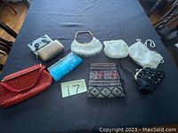 Photo of 8 antique purses on a black cloth background showing a variety of styles including beaded, sequined, embroidered, and metal mesh purses with different colors and sizes.