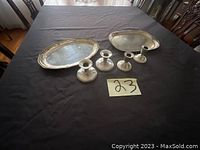 All six items arranged on a black tablecloth, including four candle holders and two oval plates