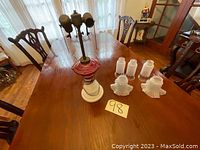 Full view of antique table lamp on wooden dining table with four white frosted glass lamp shades around it.