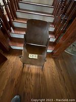 Front view of the antique wooden folding chair displaying curved backrest and flat seat with number tag on seat.